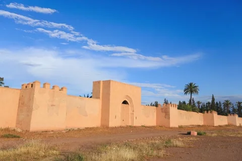 Fast moving clouds and people walking in front of the old city wall of Marrakech Stock Footage 200446699