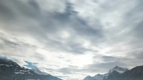 Fast moving clouds over massive snowy mountain peaks in rural Switzerland Video stock 166551733