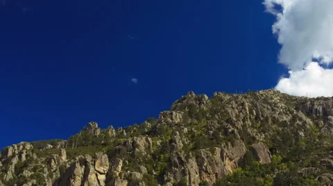 Fast moving clouds over rocky mountains, shadows running, cinematic time-lapse Stock Footage 40201350