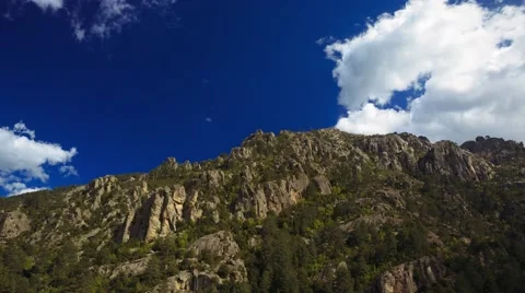Fast moving clouds over rocky mountains, shadows running, cinematic time-lapse Stock Footage 40201508