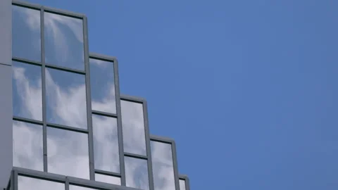 Fast moving clouds reflected in office windows against blue sky Stock Footage 135201587