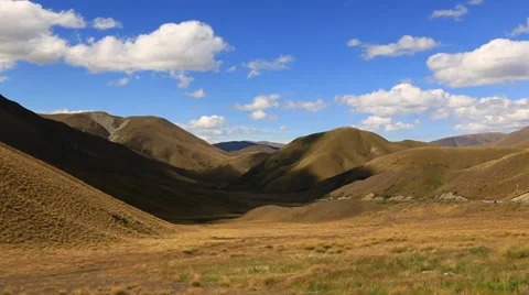 Fast moving clouds in very blue sky across rolling hills of New Zealand Stock Footage 34338505