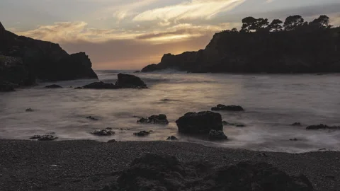 Fast moving ocean sunset timelapse with silhouetted rocks and cloudy skies Stock Footage 219354743