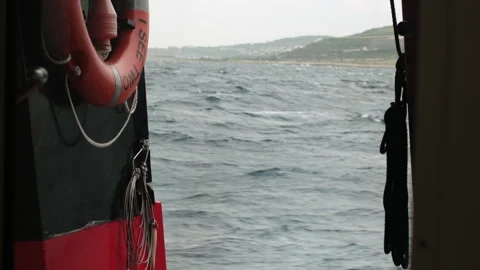 Fast-Moving Ship Deck View of Rocky Coastline under Overcast Sky Stock Footage 330863362