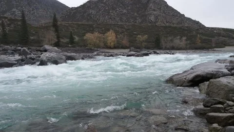 Fast moving stream of seething mountain river runs along stone banks Stock Footage 224535449