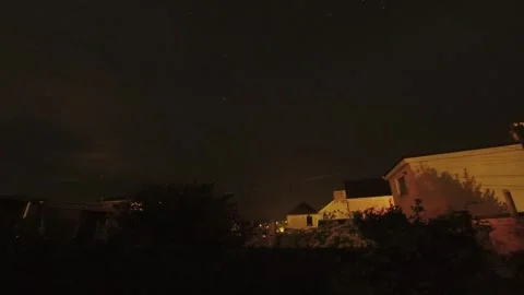 Fast moving time lapse clouds passing night sky above illuminated Welsh homes Stock Footage 341552692