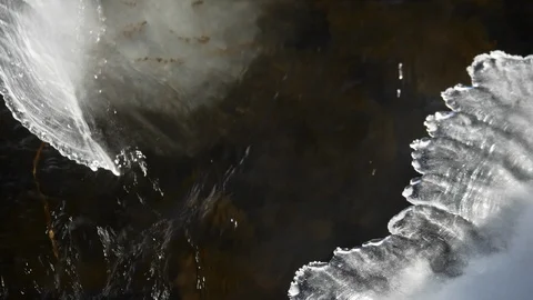 Fast moving water flows past ice formed in stream bed. Stock Footage 99995989