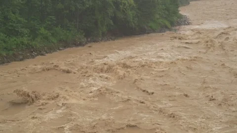 Fast muddy floodwaters rush through river channel with violent flow - Heavy Rain Vidéo 339744045