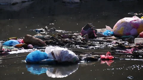 Fast pan on a flowing river with plastic and garbage pollution. Stock Footage 285561710