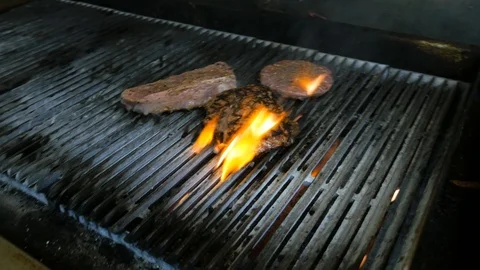 Fast pans across flame grill with steaks Stock Footage 94264632