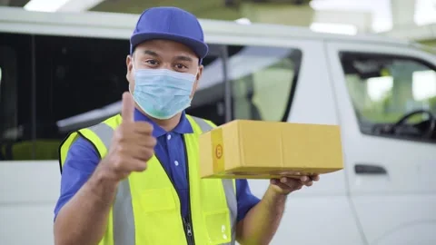 Fast post shipment service concept. Young asian deliveryman wearing face mask to Video stock 137630410