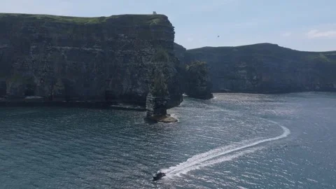 Fast RIB Curving Away From Sea Stack Below Tall Irish Coast 库存影片 341019853
