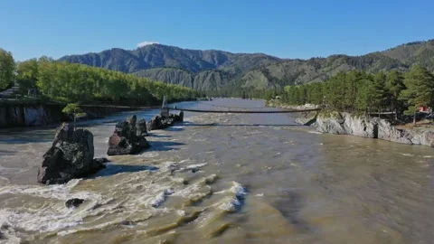 Fast river with suspension bridge in mountainous area, filmed from quadcopter. Stock Footage 305637373