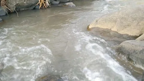Fast river water flowing with white foam over submerged rocks in natural stre Stock Footage 340457763