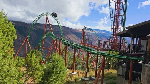 Fast roller coaster descends through a green steel loop on a steep Colorado Stock Footage 346030793