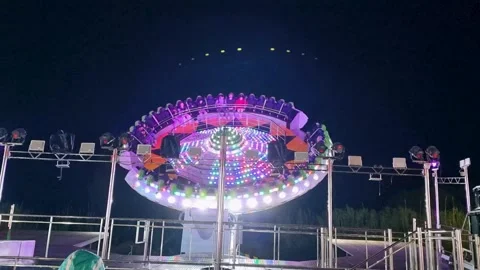 Fast Rotating Area 51 Carnival Ride Fully Illuminated with Vibrant LED Lights Stock Footage 335442892