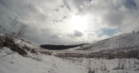 Fast running clouds and dry grass sways in the white snow-covered valley Stock Footage 46718850