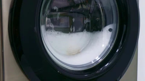 Fast spinning washing machine drum rotating dirty clothes with water 스톡 동영상 268852065