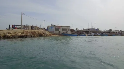 Fast stable tracking shot from a speedboat of the coastline of a small village Stock Footage 111885536