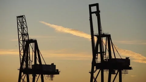 Fast sunrise pan from two container cranes to warehouse across San Francisco Bay Stock Footage 233902685