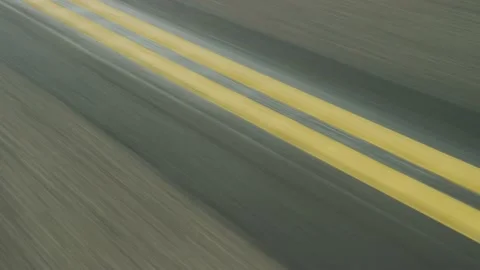 Fast tracking shot above double yellow lines on paved two lane highway Vidéo 234037779