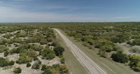 Fast tracking shot of cyclist riding through grassland biome drone aerial 4K Stock Footage 111316670