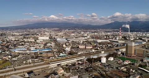 Fast train through Shin Fuji city train station in view of Mt Fuji as 4k aerial. Stock Footage 136981704