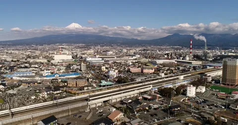 Fast train through Shin Fuji city train station in view of Mt Fuji as 4k aerial. Stock Footage 144245384