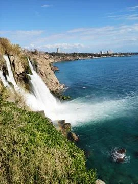 A fast waterfall falling from  mountain cliff into the blue sea Stock-Fotos