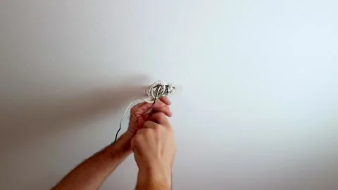 Fasten a screw on a ceiling light mount with wires hanging from a hole Vídeo Stock 137912024