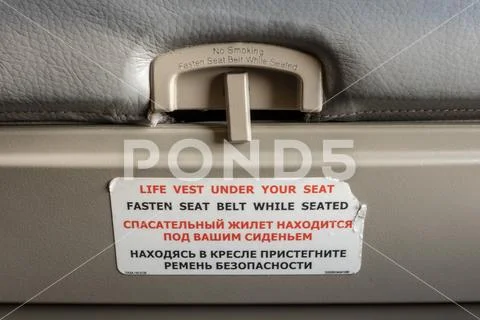 Fasten seat belt while seated symbol on the back of an airplane seat. Stock Photos