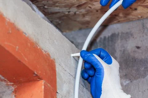 Fastening the cable to the wall. 库存照片
