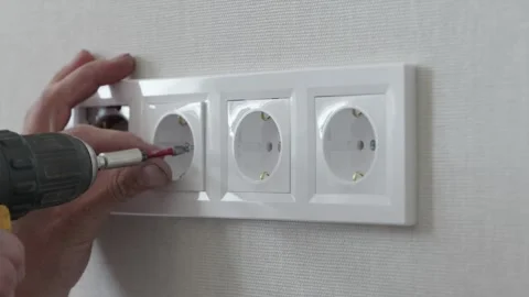 Fastening four gang electrical socket frame with cordless screwdriver tool Video stock 345039453