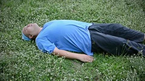 A fat bald head Thai man is exhausted and drop himself on the grass Stock Footage 63214616