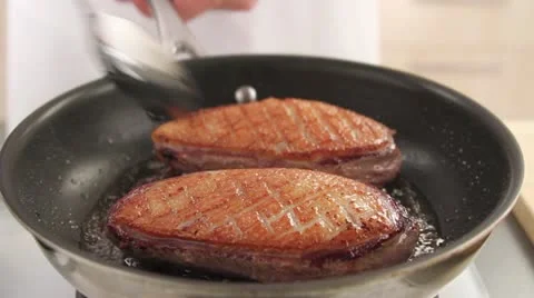 Fat being poured over duck breast skin Stock Footage 24651194