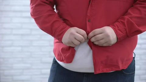 Fat belly man buttoning up red shirt and pulling down, oversize cloth problem Stockbeeldmateriaal 89443793