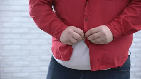 Fat belly man buttoning up red shirt and pulling down, oversize cloth problem Stockbeeldmateriaal 89450699