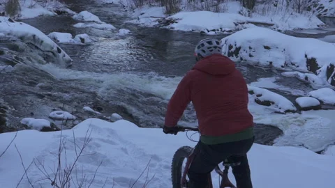 A fat biker by a river in winter Stock Footage 144786608