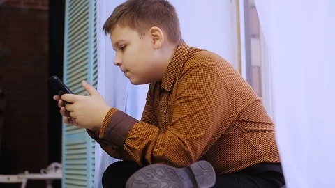 Fat boy playing on smartphone Stock Footage 99939056