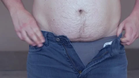 Fat caucasian man tries to fasten jeans Stock Footage
