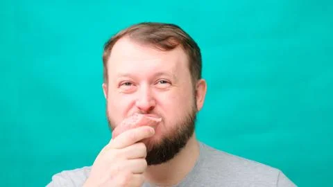 A fat chubby man with a beard eats sausage or meat, a concept of harmful Foto stock