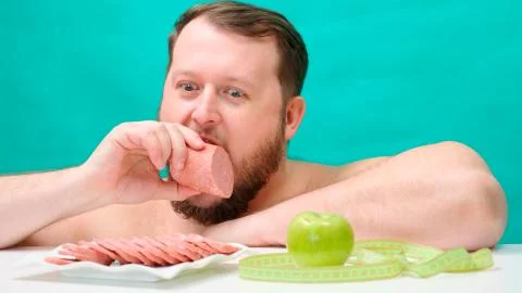 A fat, chubby man with a beard made a choice towards sausage and unhealthy Stock Photos