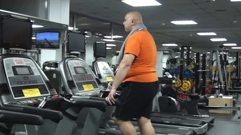 Fat cute man going on the treadmill with funny solemn look Stock Footage 96553711