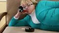 Fat depressed senior woman lying on the couch and drinking brandy HD Footage