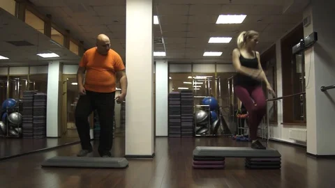 Fat funny man trying to do steps near young sportswoman 스톡 동영상 97092193