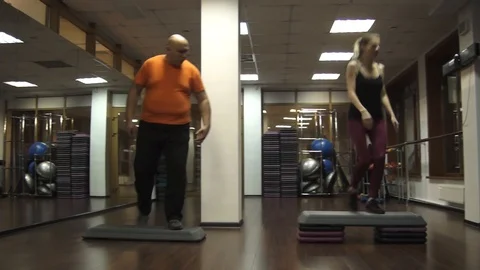 Fat funny man trying to do steps Near young beautiful young sport woman 스톡 동영상 97092217