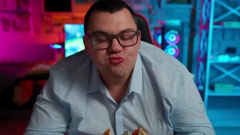 The Fat gamer plays at the computer and eats a burger and pizza. A Thick program Stock Footage 220419931