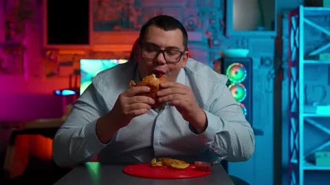The Fat gamer plays at the computer and eats a burger and pizza. A Thick program Stock-Footage 220419961
