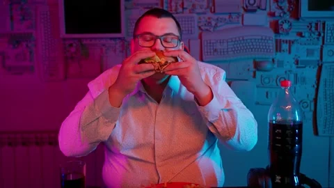 The Fat gamer plays at the computer and eats a burger and pizza. A Thick program Stock Footage 220420051