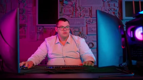 The Fat gamer plays at the computer and eats a burger and pizza. A Thick program Stockbeeldmateriaal 220420593
